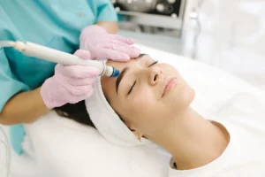 A woman getting her face cleaned by an esthetician.