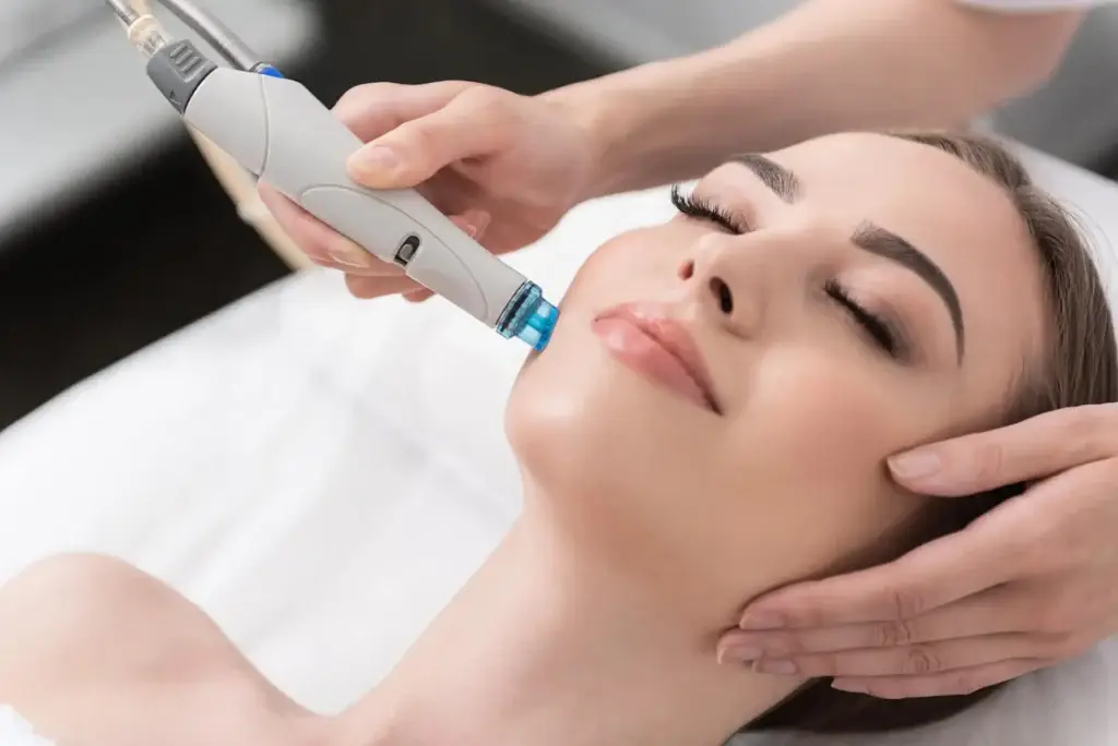 A woman getting her face cleaned with an electric device.